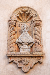 exterior view of an architectural detail on an adobe chapel building in the Tlaquepaque Arts & Shopping Village in Sedona, Arizona with religious figure wearing crown and halo