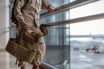 Low angle of American soldier in camouflage standing at the window