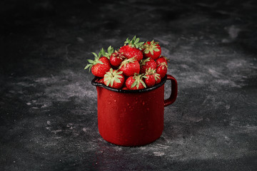 Strawberries in a bucket on the dark concrete background