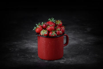 Strawberries in a cup on the dark concrete background