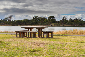A picnic table on the edge of a lake in a large community park.