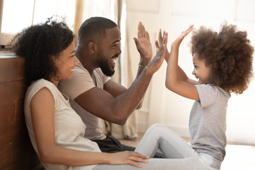 African kid daughter give high-five to daddy playing with parents