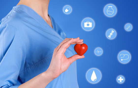 Doctor holding small heart on color background. Prevent heart attack