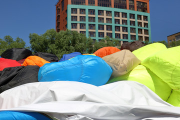 Chaotically heaped soft multi colored armchairs-bags in a city park