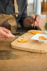 Obraz na płótnie Canvas Waiter preparing a cocktail cutting orange