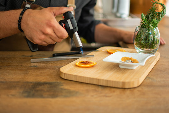 Barman burns orange with gas torch in bar