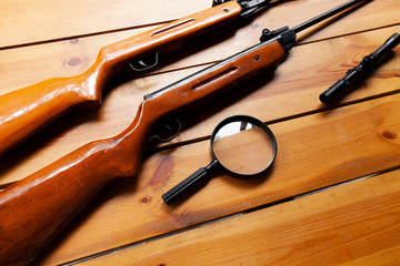 Magnifying glass laying on a table next to rifles