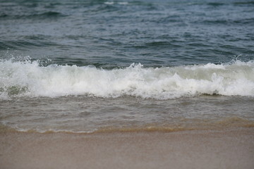 closeup on waves hitting the beach on a sunny summer day