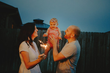 Happy Couple doing sparkler fireworks with baby