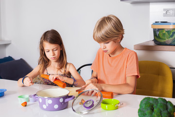 Brother and sister cutting vegetables,kids helping in the kitchen,healthy life concept