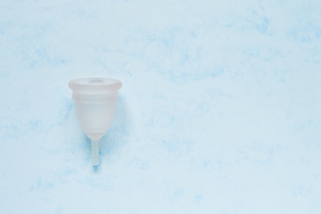 Menstrual cup on blue background. Alternative feminine hygiene product during the period. Women health concept. Copy space