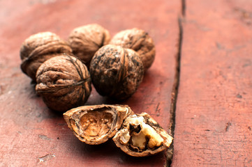 Whole and cracked walnut shells and cores closeup on old wooden boards surface as background