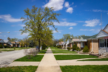 Fototapeta na wymiar Suburban neighborhood sidewalk with manicured lawns and matching houses
