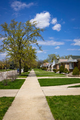 Suburban neighborhood sidewalk with manicured lawns and matching houses
