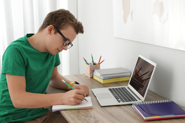 Teenager boy doing his homework at desk indoors © New Africa