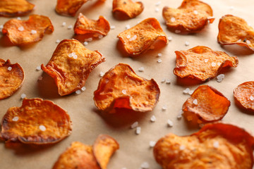 Sweet potato chips with salt on color background, closeup