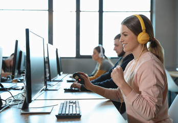 Emotional woman playing video game in internet cafe