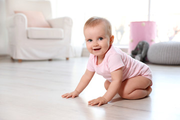 Cute baby girl sitting on floor in room