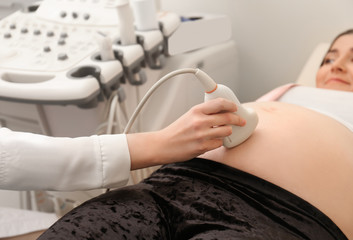Pregnant woman undergoing ultrasound scan in clinic, closeup
