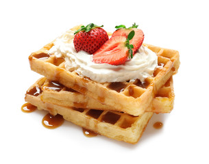 Yummy waffles with whipped cream, strawberries and caramel syrup on white background