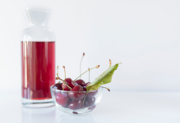 A bowl of cherry with a carafe on a white background, close up