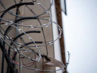 Close view of barbed wire razor wire on top of fence outside of a building in overcast
