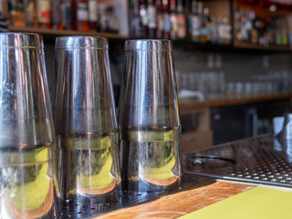Multiple steel drink shakers sitting on bar countertop ready to make cocktails