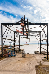 Stationary boat lift, chain hoists, structural beams, at waters edge.