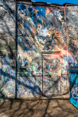 Colorful graffiti on side of building with tree shadows, energy
