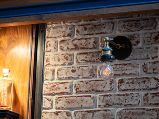 Incandescent rustic light bulb with stylized filament hang on brick wall