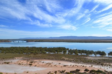 Broad bend in a river with vast wispy cloud sky and rail bridge in the distance in the South Australia Flinders Ranges