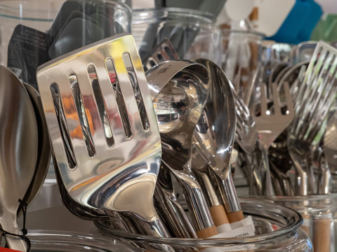 Shiny metal spatula with reflections on display with other utensils