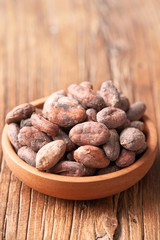 dried cacao beans in the wooden bowl, on the wooden board