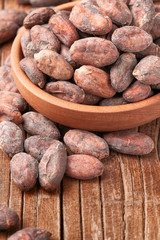 dried cacao beans in the wooden bowl, on the wooden board