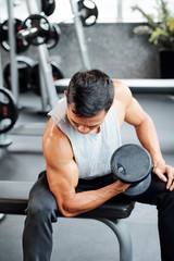 Fit strong young man doing biceps exercise with heavy dumbbells