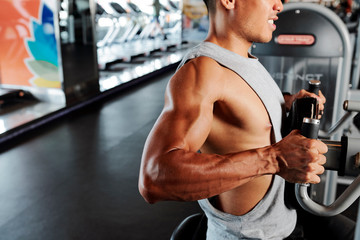 Strong fit young man doing chest exercise in gym machine