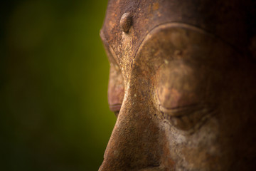 Detail of face and third eye of aged stone statue buddha 