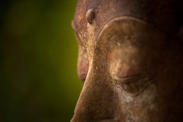 Detail of face and third eye of aged stone statue buddha 