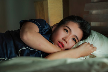 home lifestyle portrait of young beautiful sad and depressed Asian Chinese woman awake in bed late...