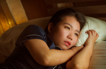 home lifestyle portrait of young beautiful sad and depressed Asian Korean woman awake in bed late night suffering anxiety crisis and depression problem feeling desperate