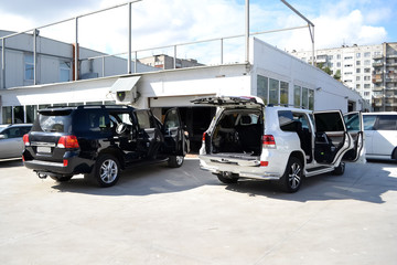 Tuning two car in a SUV white and black body with three layers of noise insulation with opened doors and trunk standing outdoor туффк the workshop. Sound and vibration isolation using soft material