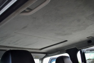 The ceiling of the SUV car with sunroof pulled by gray soft material in the workshop for tuning and...