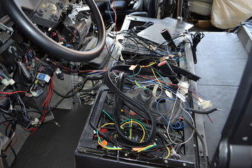 A lot of ravel multicolored wires from the car wiring lies in the cabin of dismantled car with connectors and plugs, a view through the window inside the battered car. Auto service industry