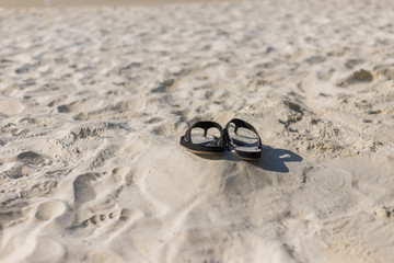 Summer holiday concept. Black pair of sandals on beach.