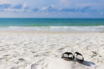 Summer holiday concept. Black pair of sandals on beach.
