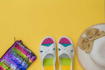 Hat, multi-colored shoes and bag on a yellow background. The concept of summer vacation. Flat lay.