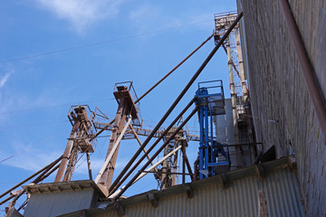 Partial view of equipment at an old California feed and grain silo and warehouse with blue sky and some clouds above