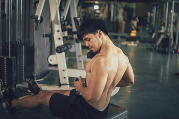 Fototapeta na wymiar Asian sportsman pull still weight for building muscle at indoor gym.