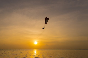 Silhouette of Paramotors flying to sky on sunset.
