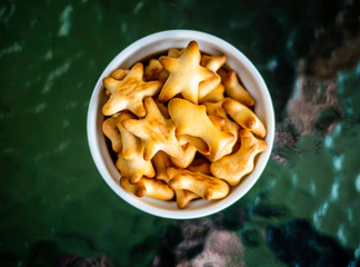 Close-up of healthy low calorie animal crackers in small cup placed on glass table.